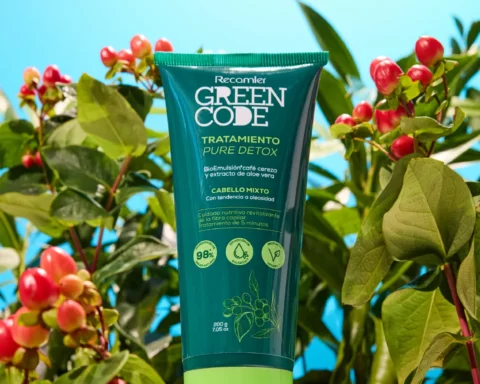 Tube of Recamier Green Code Tratamiento Pure Detox hair treatment, teal packaging with green cap, surrounded by leaves and red berries against a bright blue background.