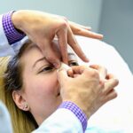 Medical professional inserts nasal gauze into a patient’s nostril during a procedure, patient lying down.