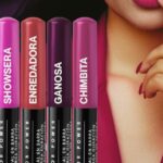 Five bright lipstick tubes with vertical white text stand in a row beside a close-up of a woman's lips and finger touching her lips, highlighting pink shades.