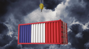 Shipping container painted in blue, white, and red being lifted by a crane against a dark stormy sky.