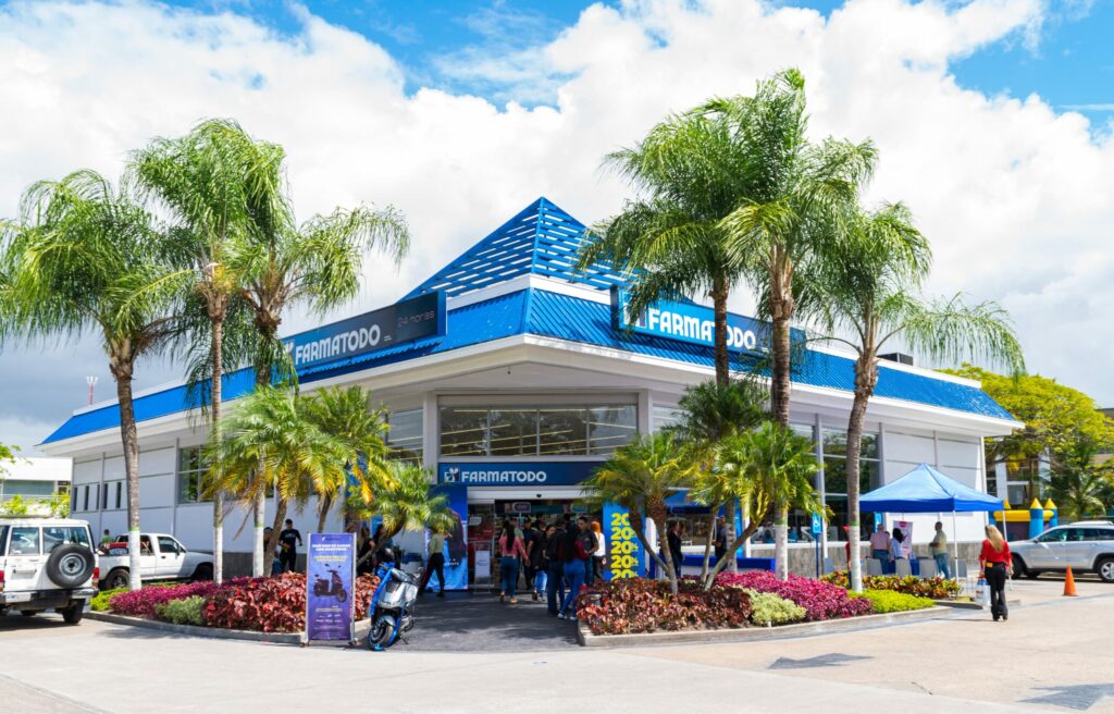 Blue Farmatodo storefront with palm trees and a clear sky, customers outside the entrance on a sunny day