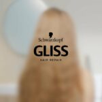 Schwarzkopf GLISS hair repair logo centered on a blurred background with a person silhouette behind it