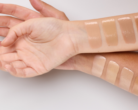 Multiple makeup foundation swatches in beige to tan tones along forearm for shade comparison on a light background.