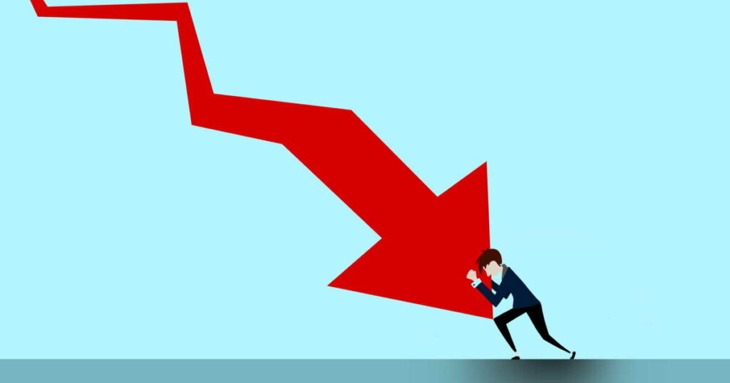 Man in a suit struggles to push a large red arrow that points downward, set against a blue background.