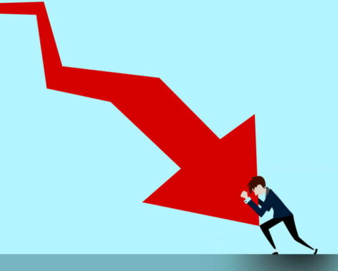 Man in a suit struggles to push a large red arrow that points downward, set against a blue background.